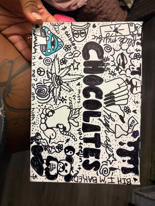 Handmade sign with black and white doodles and text, held by a person.